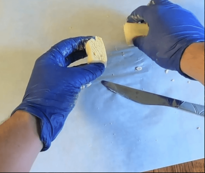 Cannabinoid matrix hash block being held after cutting showing firm cohesive texture